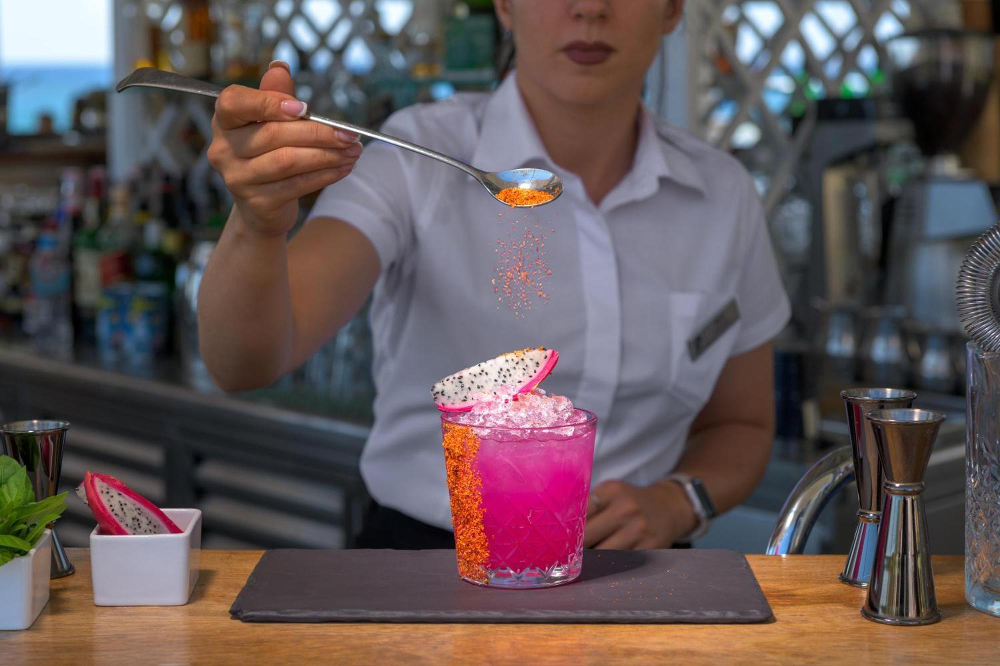 ホテル ロドス パラディウム レジャー ＆ ウェルネス Kallithéa エクステリア 写真 A bartender adding a garnish to a cocktail